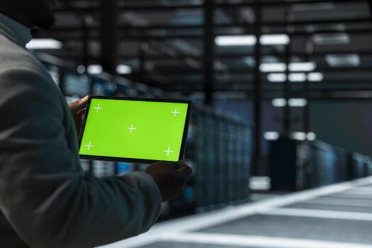Close up of data center admin using green screen tablet, doing checkup to prolong hardware life span. Server hub employee monitoring infrastructure rigs using chroma key device photo