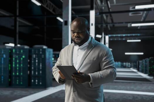 Engineer in data center using tablet to check for server performance issues arising due to high CPU usage. Server room worker fixing insufficient memory errors slowing down hardware photo