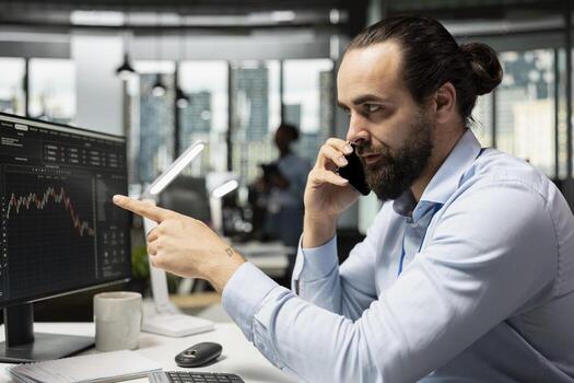 Stockbroker using smartphone to discuss with clients, executing buy and sell orders. Financial expert using mobile phone during telephone call with customer, advising on investment opportunities photo