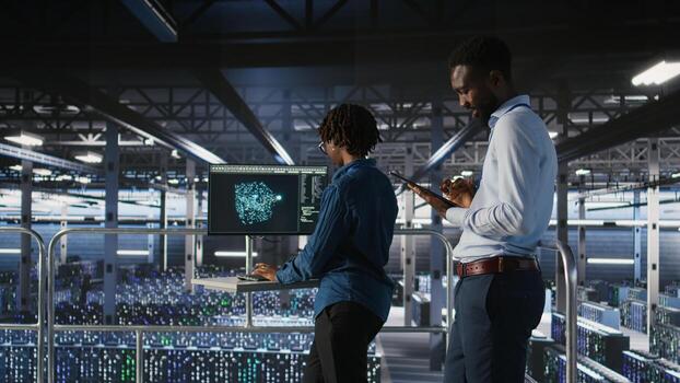 Engineers working together on data center industrial platform, completing software updates. Server hub colleagues doing brainstorming, finetuning server rig configurations, photo