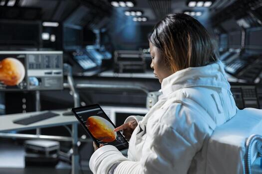 Astronaut prepares for space travel operations, reading Mars expedition status on device. Spaceman wearing spacesuit inside futuristic spacecraft monitoring red planet surface scan data on tablet photo