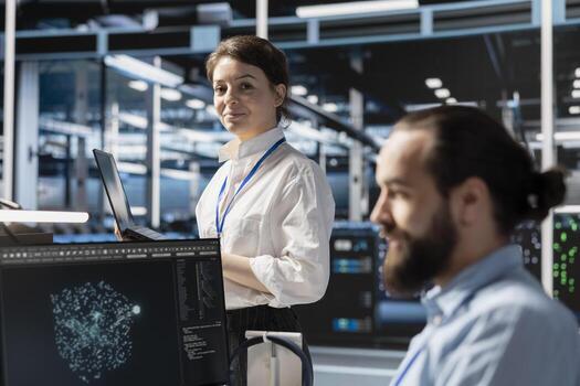 Portrait of smiling data center technician analyzing software logs metrics on laptop, optimizing storage systems. Upbeat server room employee inspecting resource utilization on notebook photo