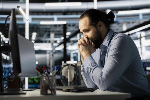 Impatient engineer in data center waiting for storage arrays software to update, configuring network virtualization. Upset man in server room annoyed by unstable system performance photo