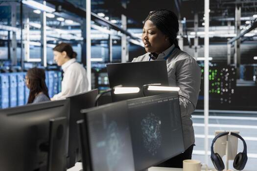 Software developer overseeing server clusters doing data intensive operations. IT expert using laptop to supervise supercomputers maintaining storage for machine learning photo
