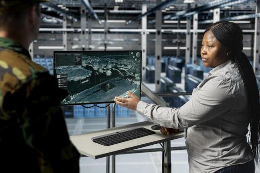 Teamworking army experts in data center confirming target locations using aerial image overlay on monitor. Military units in server room gathering strategic terrain data via satellite systems photo