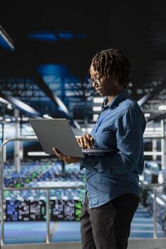 Portrait of black engineer working on data center industrial platform, completing software updates and ensuring automation. Server room expert finetuning server rig configurations. photo