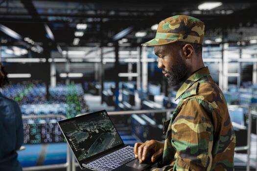 African american military officer in secure data center monitoring AI systems. Armed forces personnel in server farm ensuring stable infrastructure for deep learning defense operations. photo