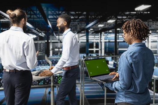 africano americano hembra supervisor revisando verde pantalla en computadora portátil, actualización servidor bastidores infraestructura. eso ingeniero utilizando Bosquejo en servidor cubo espacio de trabajo lleno con redes tecnología foto