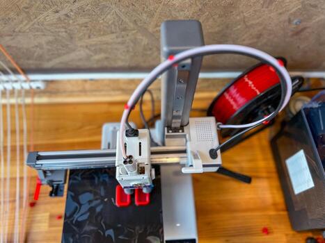 3d printer creating a prototype with red filament in a workshop photo