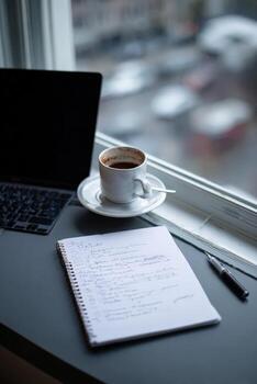A notebook and a cup of coffee on a desk photo