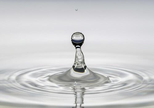 Highspeed photograph of a single water drop creating ripples on a calm surface photo