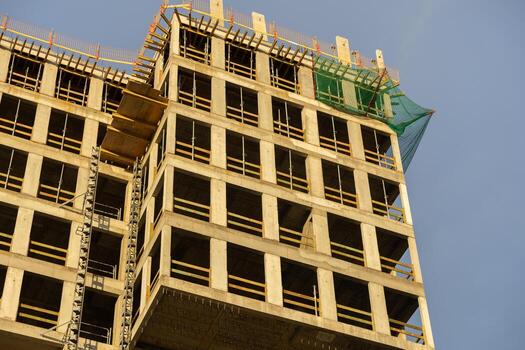 Modern concrete building under construction, showcasing its raw framework, scaffolding, and safety netting, symbolizing urban development and progress photo
