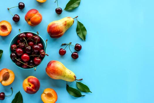 top view of cherries in bowl and pattern of peach apricot pear cherry on blue background with copy space photo