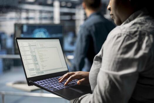 Close up of server room coworkers troubleshooting backend operations using software on laptop. Team of data center programmers compiling software patches to fix bugs using notebook photo