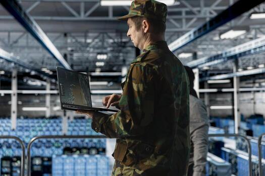 Military officer in data center monitoring warfare drone telemetry on laptop dashboard. IT specialist in army server hub using tactical interface on notebook to support aerial operations photo