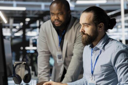 Team of technicians in data center using PC to update storage arrays software, configuring network virtualization. Teamworking colleagues in server room using computer to verify settings photo