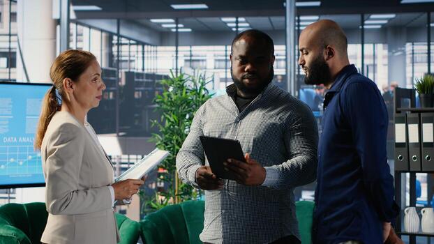 Diverse group of CEOs applying data analysis and strategic thinking to guide partnership decisions, using research and performance metrics. Multicultural perspectives in office lobby. Camera B. photo