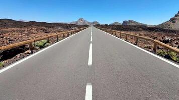 A stunningly beautiful view of a long, straight road that is bordered by rocky terrain beneath a clear blue sky video