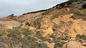 erfarenhet en fantastisk se av texturerad sluttningar med jordnära färger, gles flora, och grönska under en molnig himmel video