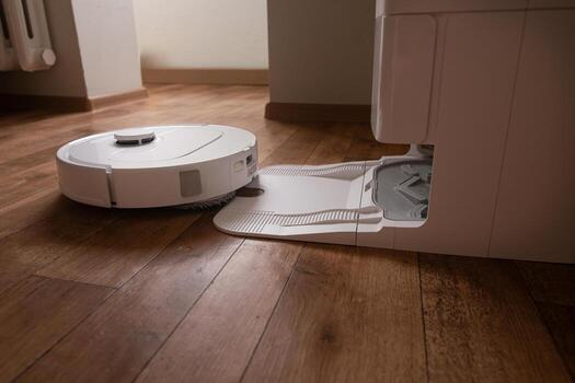 Task done the robot vacuum returns smoothly to its home base to recharge batteries and empty the dustbin without human help. photo