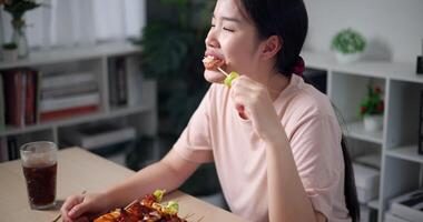 palmare alto angolo Visualizza sparo, rilassato asiatico donna godendo mangiare grigliato barbecue al chiuso, guardare contento e rilassato. video