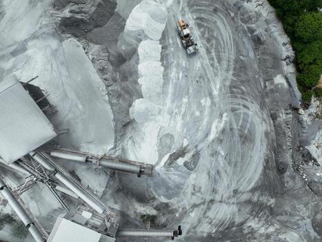 Top-down drone image of crushing plant and dust-covered trucks producing building aggregates, offering visual insight into the balance between infrastructure development and environmental footprint. photo