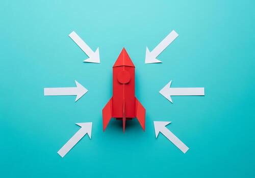 Red Paper Rocket Ship With White Arrows Pointing Towards it Centered on a Teal Background Representing Launch and Focus photo