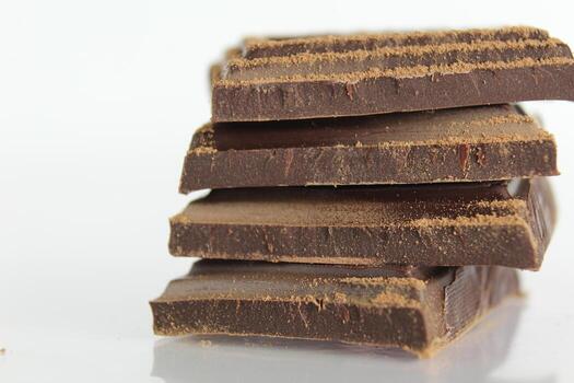 bitter chocolate pieces stacked slide lies on a white background with a reflection with a place for text and copyspace photo