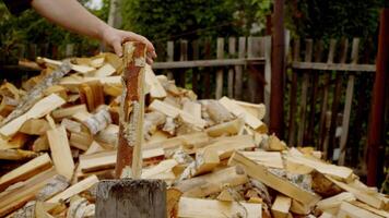 en man är skärande ved med en skarp yxa, men de yxa får fastnat i de trä, orsakar honom till ha till göra extra ansträngning till dela de logga. video