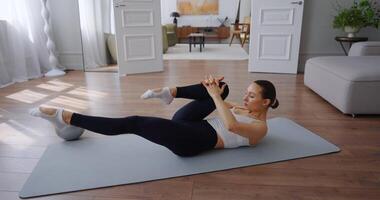 sportlich Frau durchführen Pilates Übung auf Matte im hell, modern Leben Zimmer mit natürlich Licht video