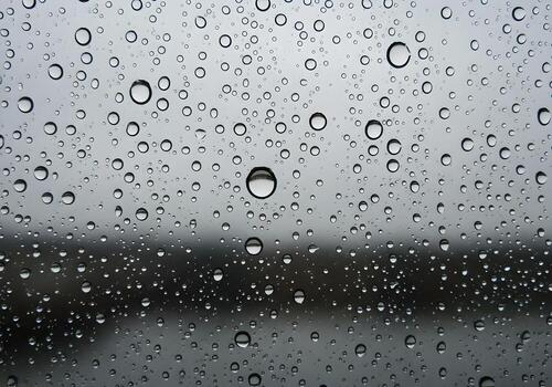Macro rain droplets on glass window with blurred nature background, clean and sharp abstract texture image with natural lighting and no human elements photo