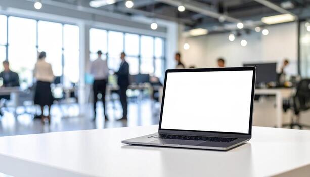 Modern office workspace with laptop white desk and blurred people working background bright natural light coming through large windows professional environment technology business setting open photo
