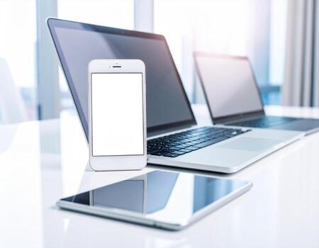 Smartphone and laptop on white table with blank screen photo