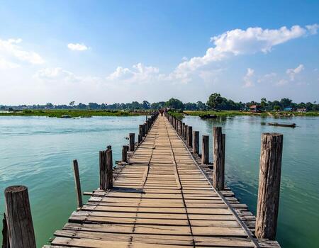 Serene view of U Bein Bridge stretching over tranquil waters in Amarapura, Myanmar, showcasing ancient wooden planks photo
