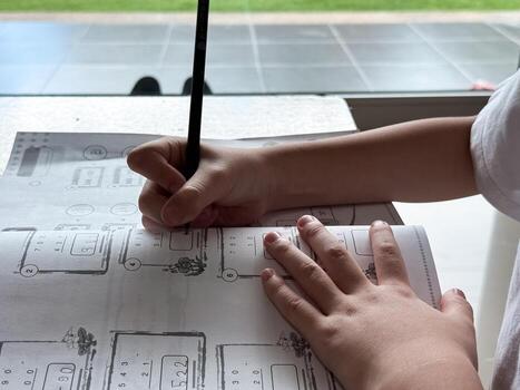 A young student sits at a wooden desk working on basic math exercises, steadily developing essential problem solving skills.j photo