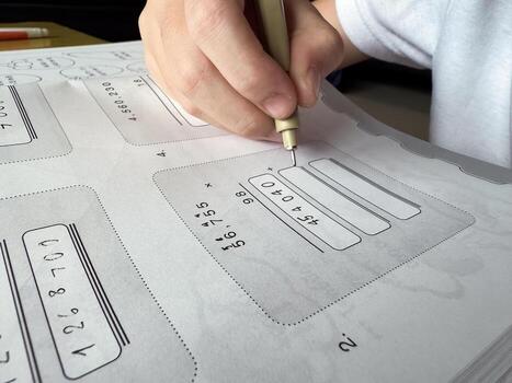 A young student sits at a wooden desk working on basic math exercises, steadily developing essential problem solving skills.i photo