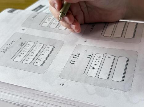 A young student sits at a wooden desk working on basic math exercises, steadily developing essential problem solving skills.k photo