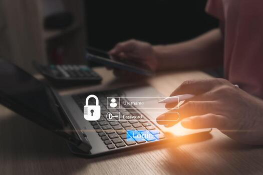 Concept of logging into online website on laptop using personal username and password to prevent fraud and for cyber security. Businessman sitting working in a room with only one illuminated spot. photo