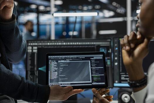 Close up of programmers coding on tablet in data center, refining algorithms for faster processing. IT workers using device in server room, conducting tests using software photo