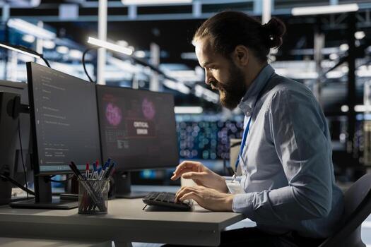 Server room IT expert trying to repair malicious threats using detection tools. Data center programmer coding fixes after systems detect irregular network activity patterns photo