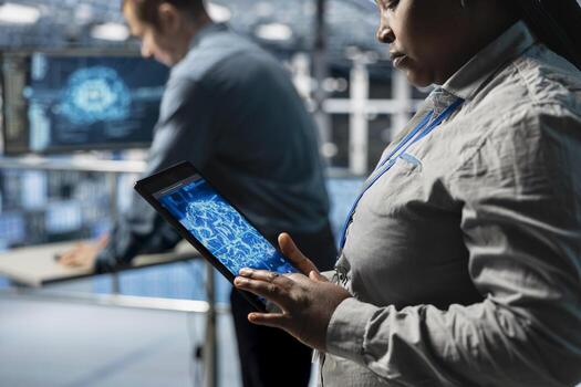 Close up of IT professional in server farm using tablet to improve AI system scalability for increased workloads. Data center engineer using device to adjust artificial intelligence model parameters photo