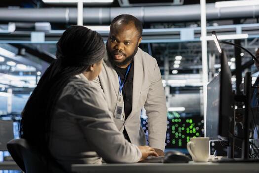 Data center engineering team running diagnostic scripts on computer, examining hardware. Server room teamworking colleagues using PC to evaluate performance metrics, maintaining system stability photo