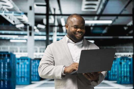 Smiling technician in data center workspace running system diagnostic tests and error checking utilities to fix problems. Happy employee looking for network issues affecting rigs performance photo