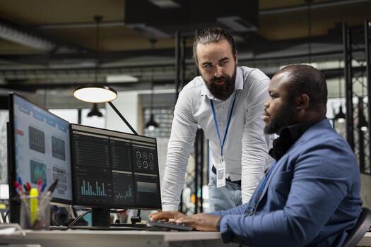 Diverse corporate team focuses on data management on computer, planning strategies for company growth and aligning objectives with performance metrics for measurable productivity. photo