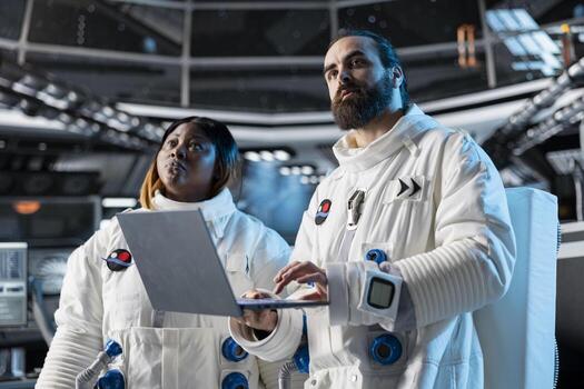 Team of astronauts in spacecraft using laptop to run telemetry data analysis. Teamworking spaceship crew colleagues in spacesuits analyzing mission logs on notebook during planetary exploration photo