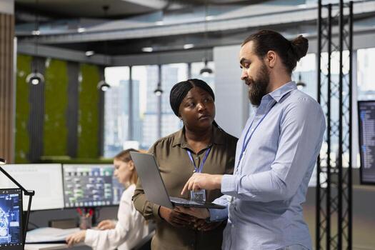 Teamworking programmers collaborating at work to train deep learning models for anomaly detection automation. IT staff members working together, using AI on PC in office to repair network issues photo
