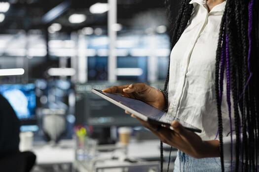 Close up of data center engineer using tablet, deploying and maintaining server and network hardware. Server hub employee using device to manage large scale IT infrastructure photo