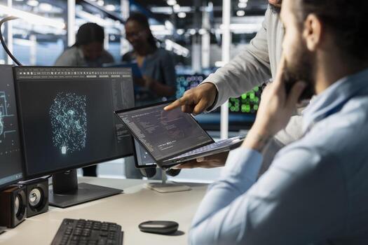 Close up of data center admins monitoring system performance using laptop, identifying bottlenecks. Server farm IT experts using notebook to troubleshoot glitches, implementing optimizations photo