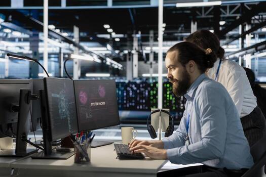 Engineers in data center reacting to ransomware alert on PC monitor, initiating protocol to protect critical systems. IT experts reviewing hacking attempts and assessing compromised infrastructure photo
