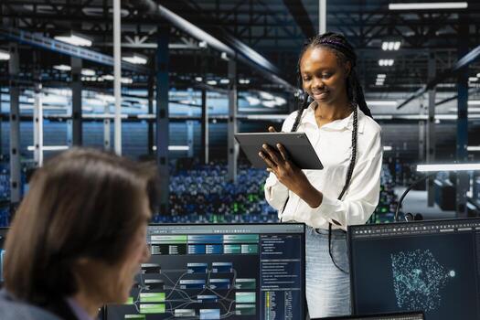 Smiling data center software developer using tablet, coding, managing systems for uptime and efficiency. Happy IT expert next to colleagues using programming languages in server hub photo